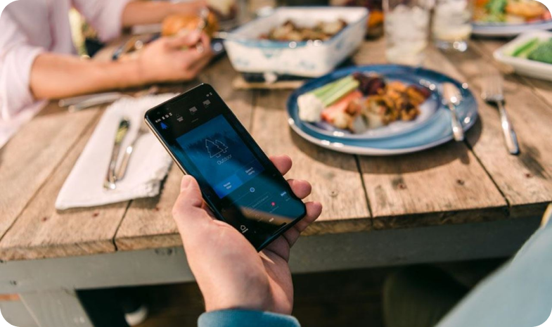 A person uses their smartphone to control their hearing aid using the hearing aid app.