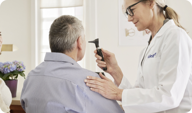 A Beltone audiologist examines a man's inner ear during a hearing evaluation.