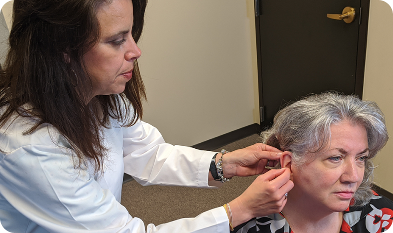 A Beltone audiologist measures a patient's ear, fitting her for a Beltone hearing aid.