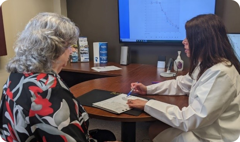 A Beltone specialist meets with an older female patient to review the results of their free hearing test.