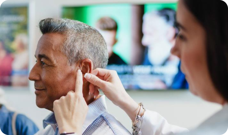 A Beltone specialist examines a patient's ear, using her hands to feel around the outside of the patient's ear lobes.
