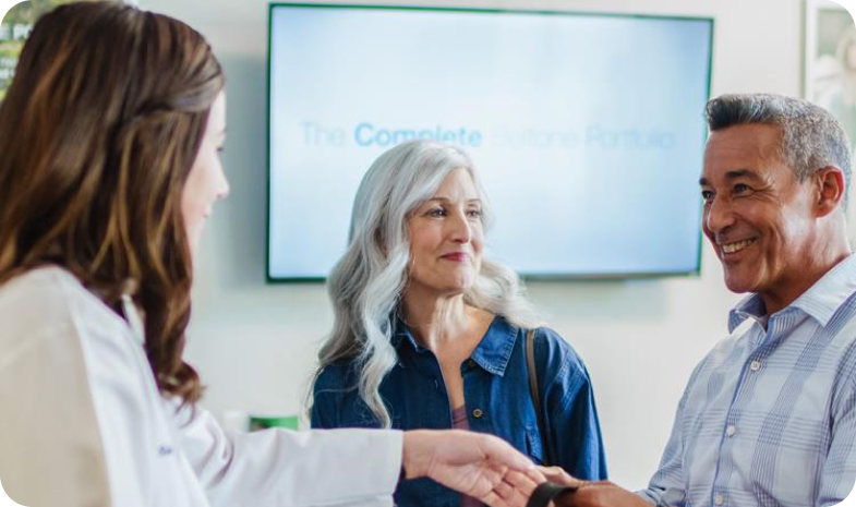 A middle-age couple meets with a Beltone hearing specialist to discuss hearing aid financing options.