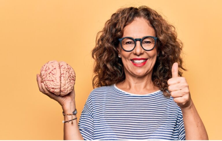 Smiling woman holding a plastic brain with a thumbs up