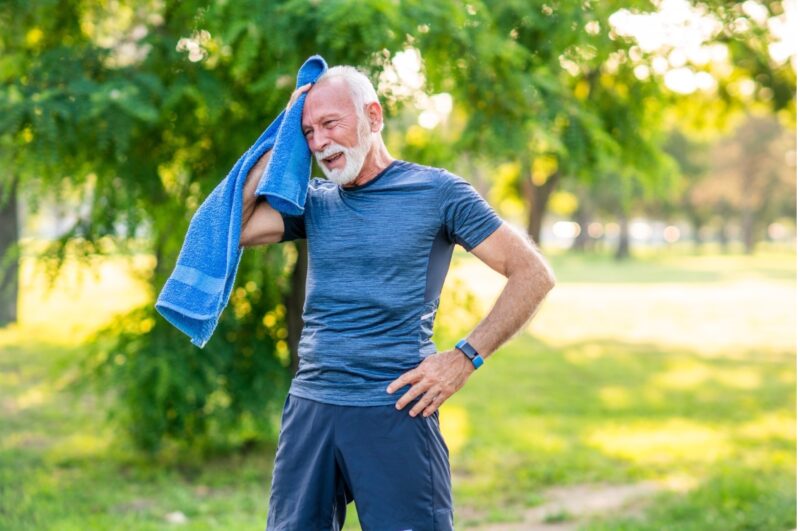 Man jogging and caring for his hearing aids in heat and humidity