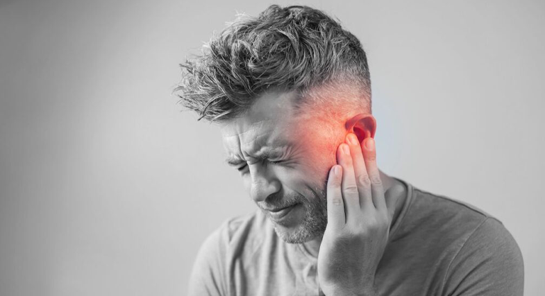 A black and white picture of a man, experiencing pain in his ear, which is highlighted red in the photo.